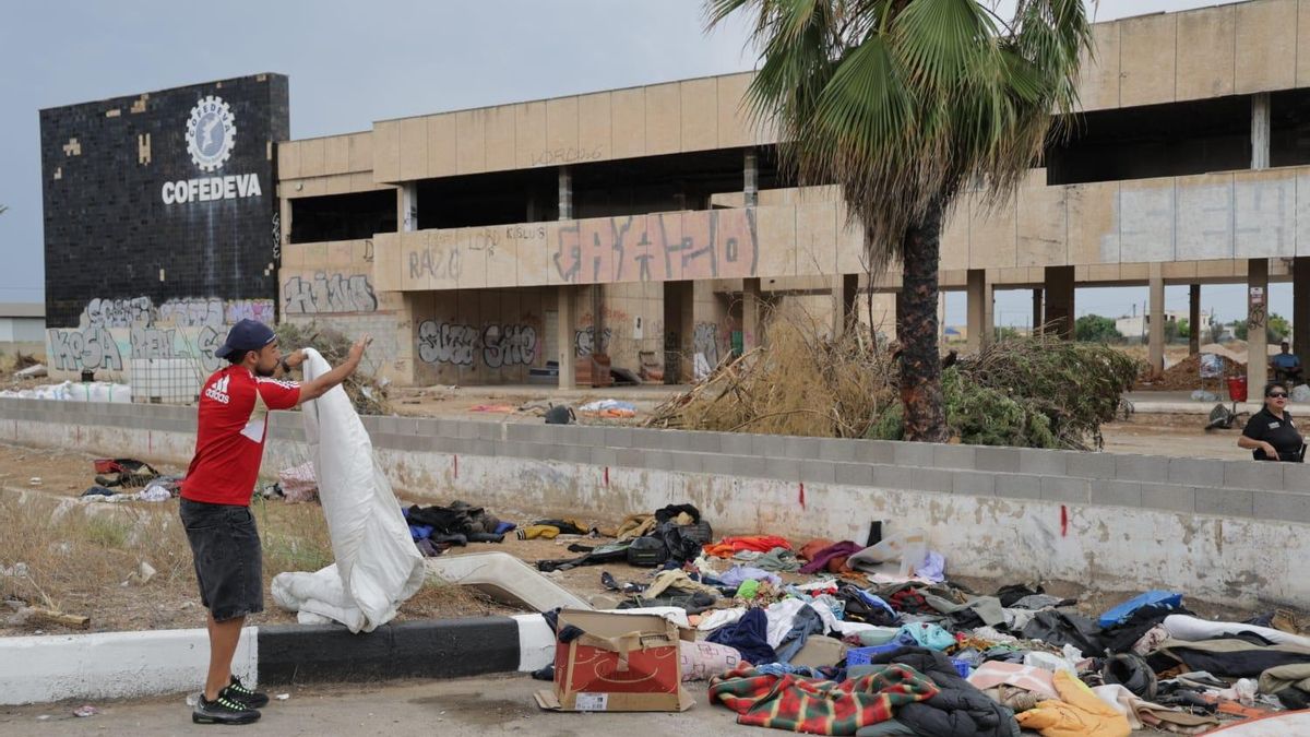 Un migrante desalojado busca entre los objetos tirados.
