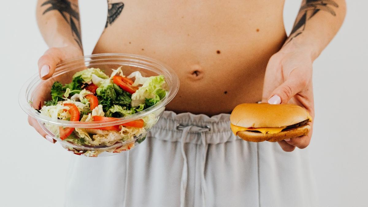 Una persona sujeta una ensalada y una hamburguesa