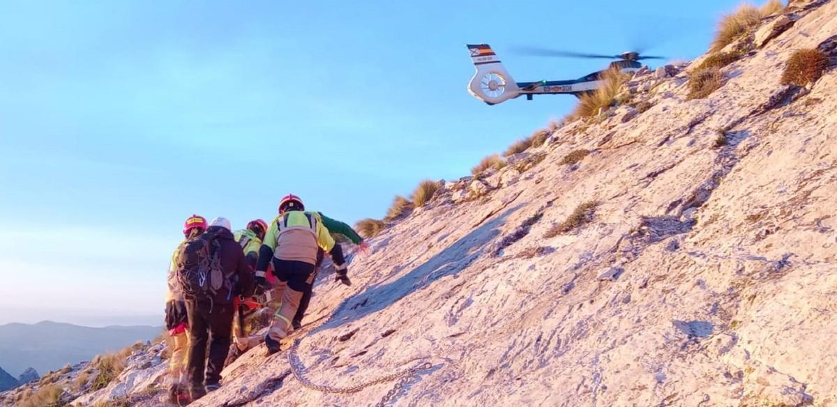 Bomberos del Consorcio Provincial y especialistas de la Guardia Civil transportan hacia el helicóptero a un senderista herido en la Tiñosa.