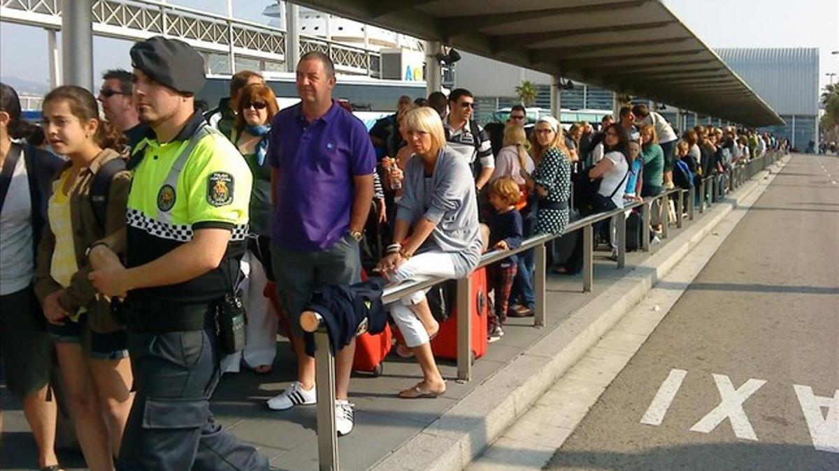 Colas de turistas llegados en un crucero esperan un taxi en el muelle Adossat.