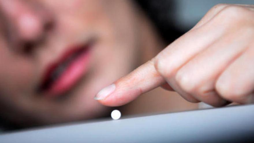 Una mujer juega con una pastilla antes de consumirla.