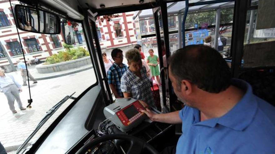 Usuarios pagando sus billetes de autobús en la parada de la calle Manuel Llaneza de Mieres.