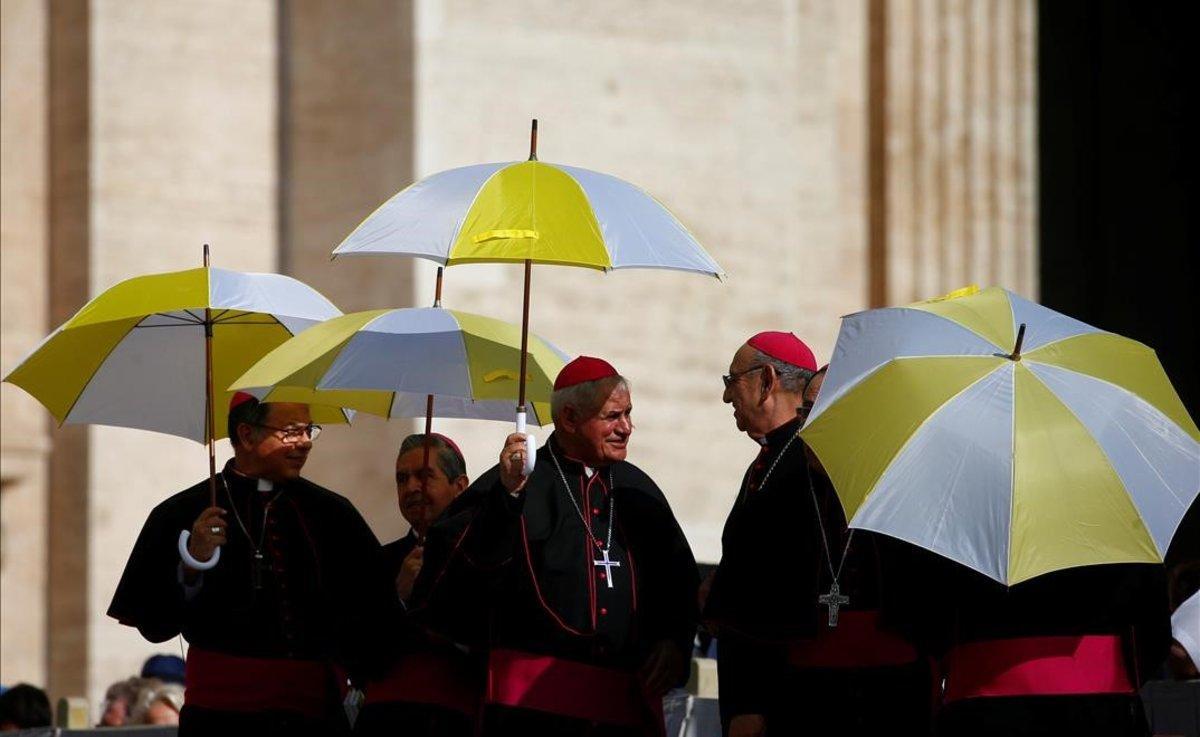 Miembros del clero se resguardan del sol con paraguas en la plaza de San Pedro, en El Vaticano.