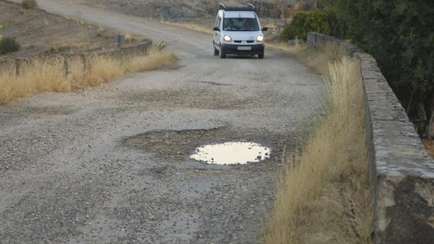 Un vehículo circula por la carretera de Robledo, donde son visibles varios de los baches.