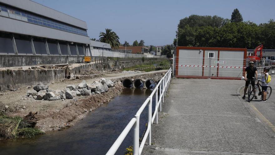 Dos ciclistas ante la zona en obras del rio Piles, a la altura del pabellón verde del Grupo Covadonga. | Ángel González