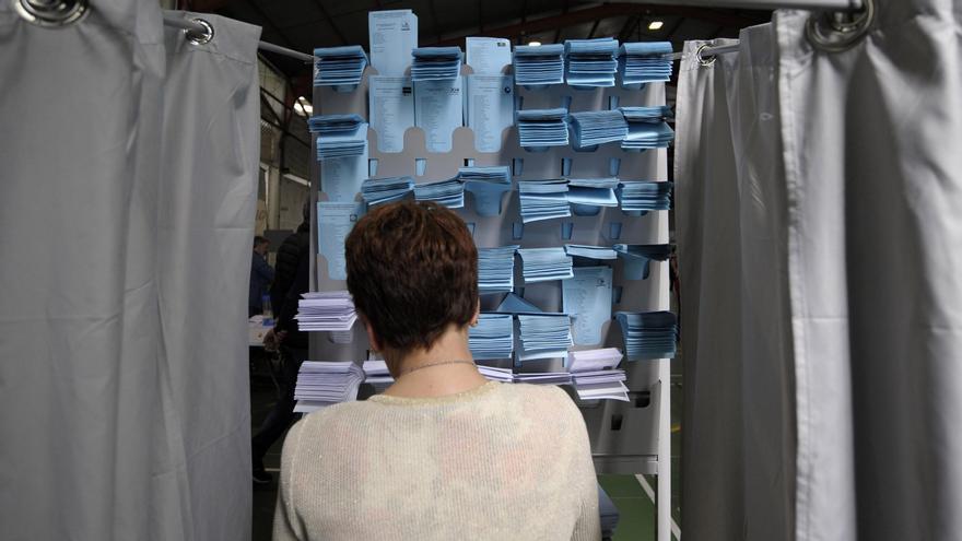 Una mujer elige papeleta en una cabina de votación en las municipales de 2019.