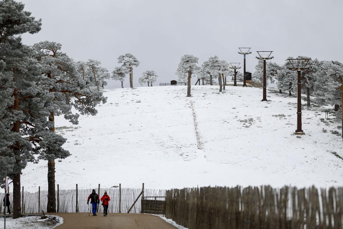 Dos personas pasean cerca de la estación de esquí de Puerto de Navacerrada, en Madrid