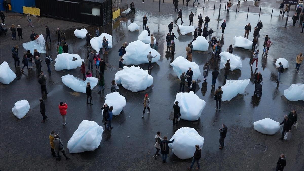 Público interactúa con pedazos de hielo fundiéndose en una exhibición islandesa y danesa en el Tate Modern en Londres.