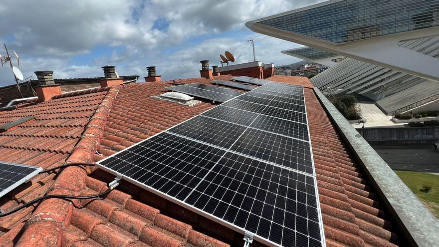 Paneles de energía solar en un tejado de Oviedo, con el edificio Calatrava al fondo.