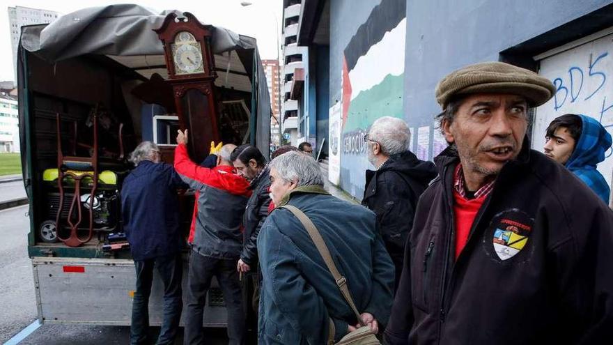 Un instante del desalojo del salón de actos de la Casa Sindical, con varias personas cargando muebles en el camión.