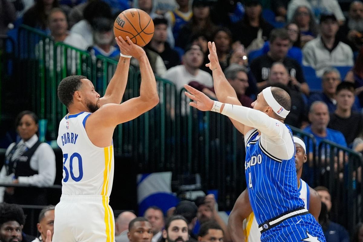 Golden State Warriors guard Stephen Curry (30) shoots over Orlando Magic guard Jalen Suggs during the first half of an NBA basketball game, Tuesday, Nov. 18, 2025, in Orlando, Fla. (AP Photo/John Raoux)