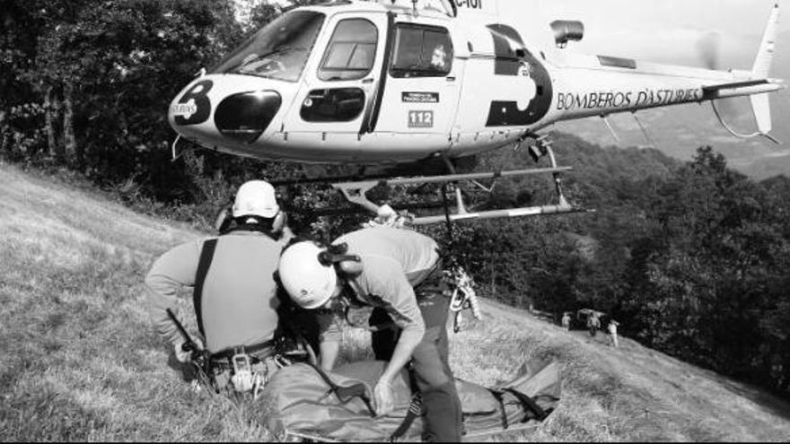 Dos rescatadores esperan a izar al helicóptero el cuerpo de una persona durante un rescate.