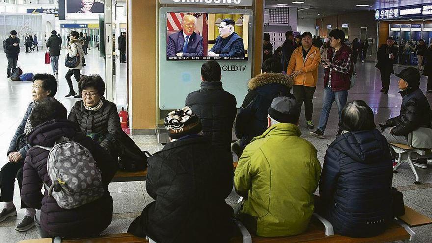 Coreanos escuchan el anuncio de la cumbre entre Trump y Kim en una estación de tren de Seúl. // AFP