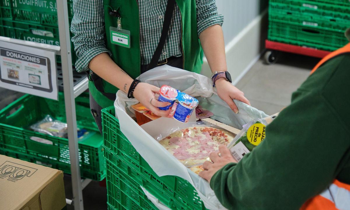 Personal de Mercadona prepara llena de productos un envase.