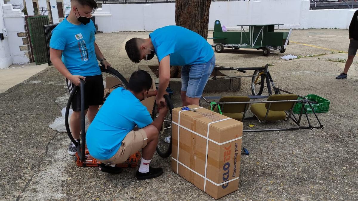 Tres de los alumnos, trabajando en un vehículo.