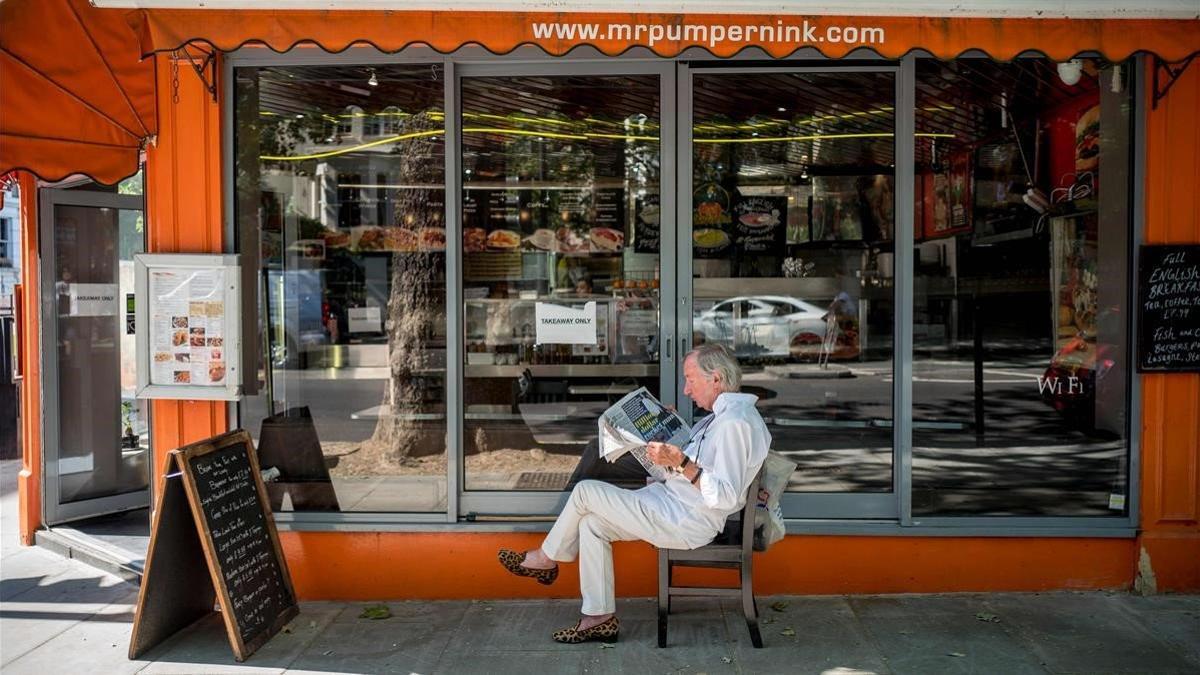 zentauroepp53612881 a man reading a newspaper outside a restaurant open for take200605201002