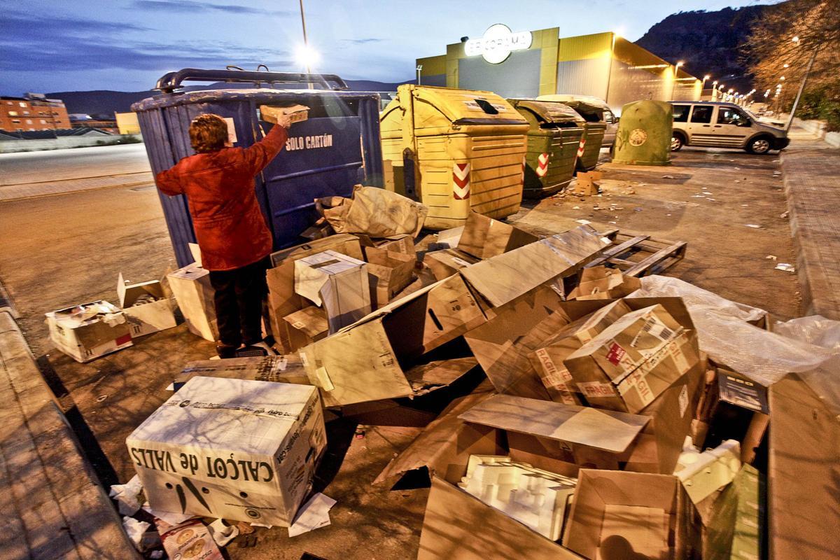 Una vecina de Alcoy depositando cartón en un contenedor.