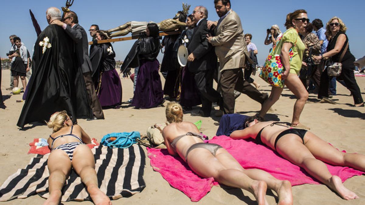Bañistas y cofrades, en la playa de la Malvarrosa de Valencia, en la Semana Santa del 2014.