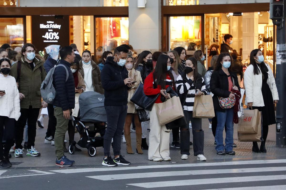 Varias personas en el centro de València tras realizar sus compras en el Black Friday.