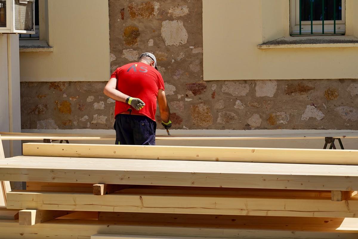 Un operario trata la madera de las vigas antes de montarlas.