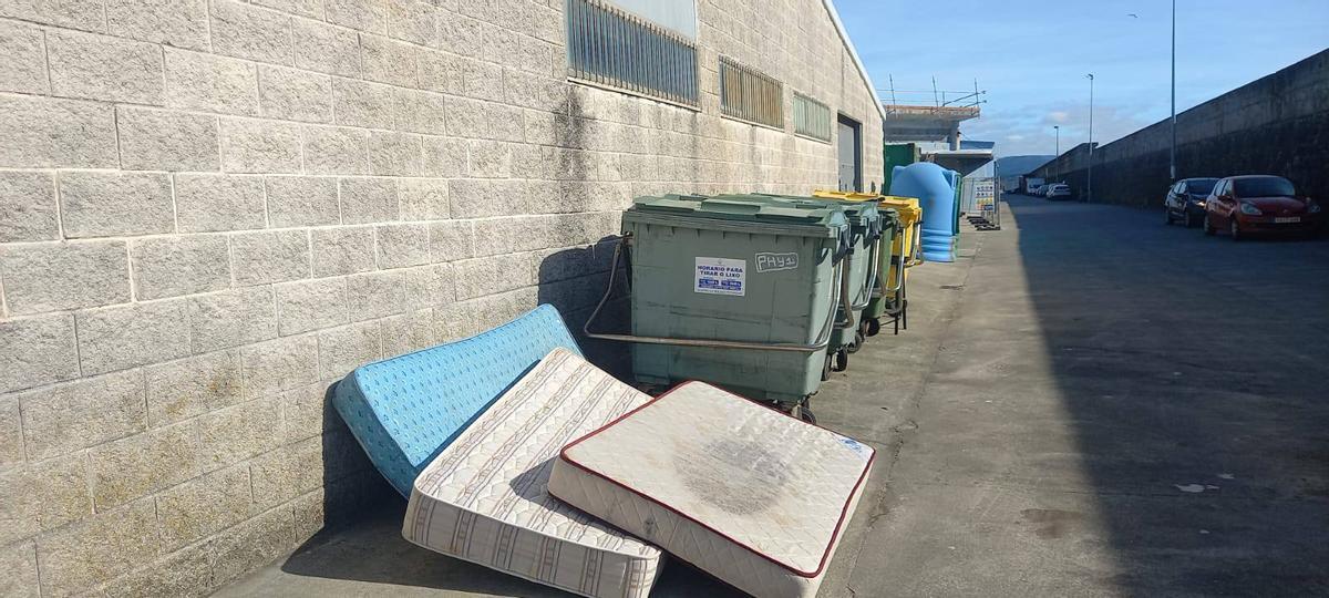 Colchóns apilados ao carón de contedores na zona portuaria.
