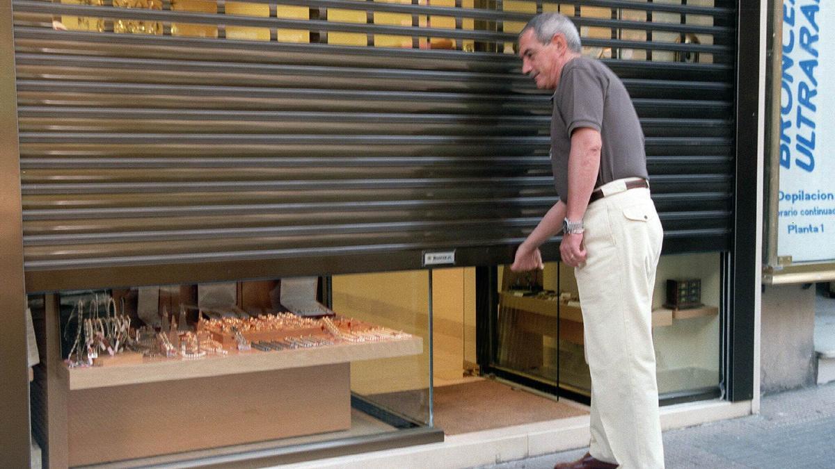 Un comerciante baja la persiana de su establecimiento.