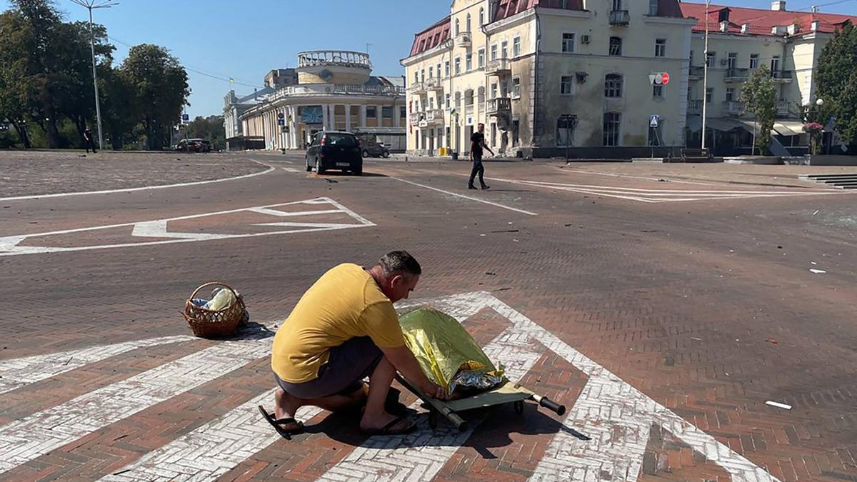Un residente de Chernígov junto al cadáver de una de las víctimas mortales por el bombardeo ruso en esta ciudad de Ucrania, este sábado.