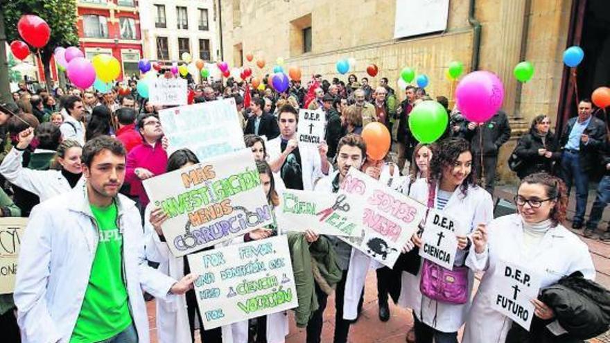 con bata y pancarta. Muchos de los investigadores que se manifestaron ayer en Oviedo, con ingeniosas pancartas, batas blancas de laboratorio y globos contra la «fuga de cerebros».  | luisma murias
