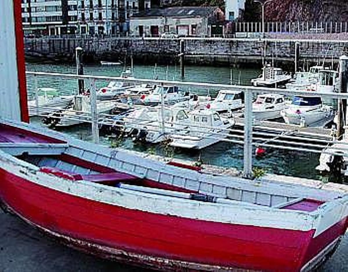 Una vieja embarcación de pesca sobrevive entre lachas deportivas, con el edificio del Náutico al fondo.