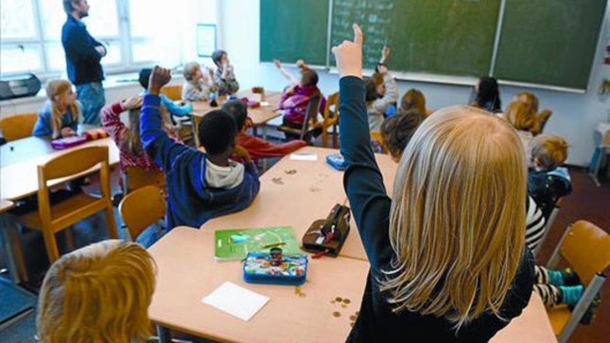 Varios alumnos levantan la mano para hablar en una escuela de educación infantil y primaria de Berlín, la semana pasada.