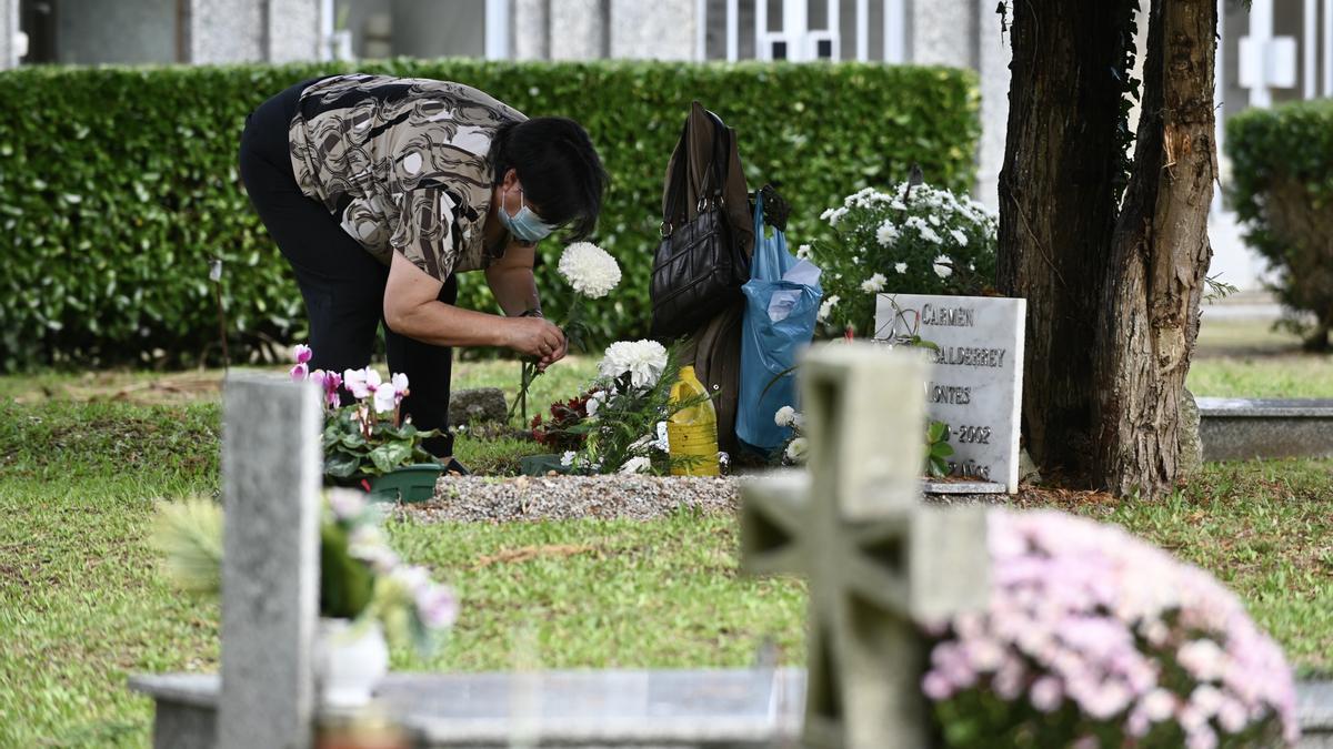 Una mujer adorna una tumba en el cementerio de San Amaro/ Rafa Vázquez