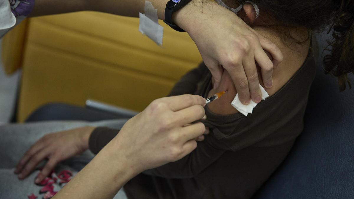 Administración de una vacuna a una niña, en pandemia.
