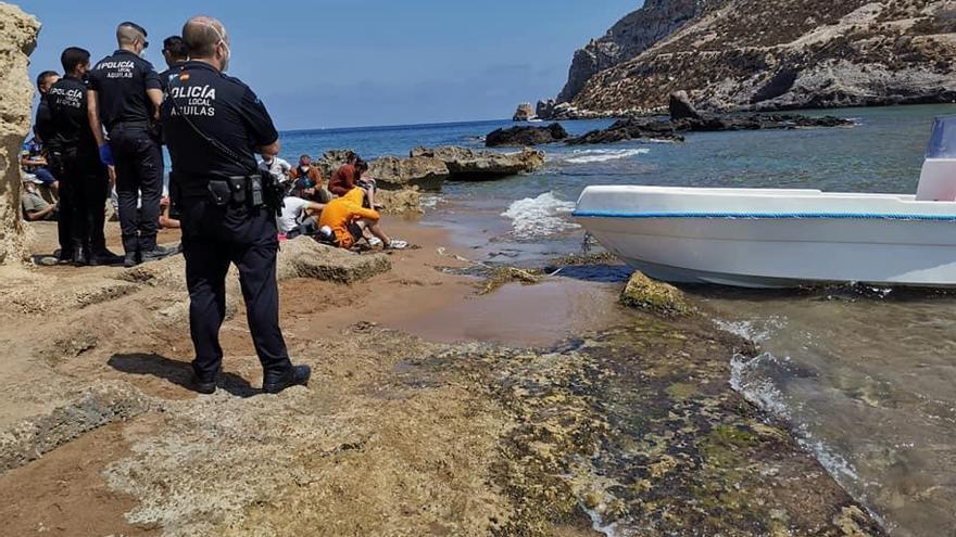 Policías de Águilas custodian a inmigrantes en la playa.