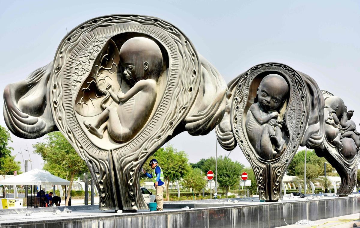 CORRECTION - Workers operate on "The Miraculous Journey", an art installation by artist Damien Hirst outside the Sidra Medical & Research Centre in Doha, on the day of their unveiling on October 10, 2018. - Fourteen giant bronze sculptures by British artist Damien Hirst graphically documenting the moment from conception to birth have been officially unveiled outside a new hospital in Qatar. "The Miraculous Journey", which culminates with a 14-metre (46-feet) statue of a just-born naked baby, is the eye-catching centrepiece of 65 separate works at Doha's Sidra Medicine Hospital, forming possibly the largest collection of art at any medical facility anywhere in the world. (Photo by - / AFP) / ?The erroneous mentions appearing in the metadata of this photo by - has been modified in AFP systems in the following manner: October 10 instead of November 18. Please immediately remove the erroneous mentions from all your online services and delete it (them) from your servers. If you have been