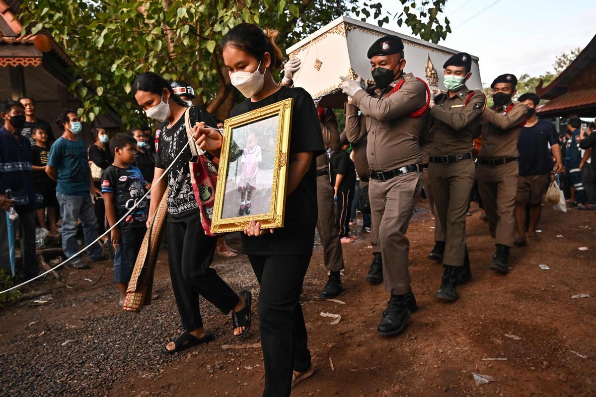 La gente observa cómo las piras funerarias incineran a 19 víctimas del tiroteo en la guardería de Uthai Suwan en el templo Wat Rat Samakee en Uthai Sawan. Un exoficial de policía disparó y mató a 37 personas, al menos 24 de ellos niños, después de irrumpir en una guardería infantil en el noreste de Tailandia.