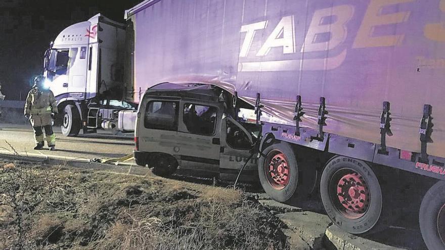 En la imagen, un bombero observa la furgoneta que quedó atrapada debajo del camión.