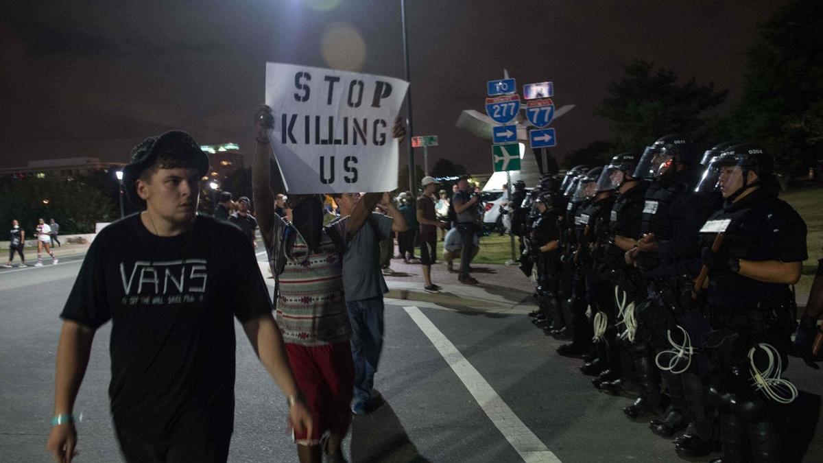 Manifestantes pasean con pancartas ante el cordón policial, esta madrugada en Charlotte.