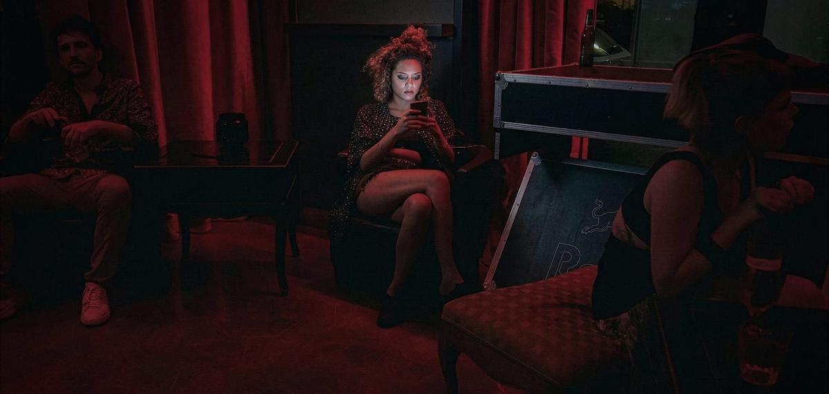 La foto contada | La flor más bella: Una mujer mira el móvil en una fiesta en Palma.