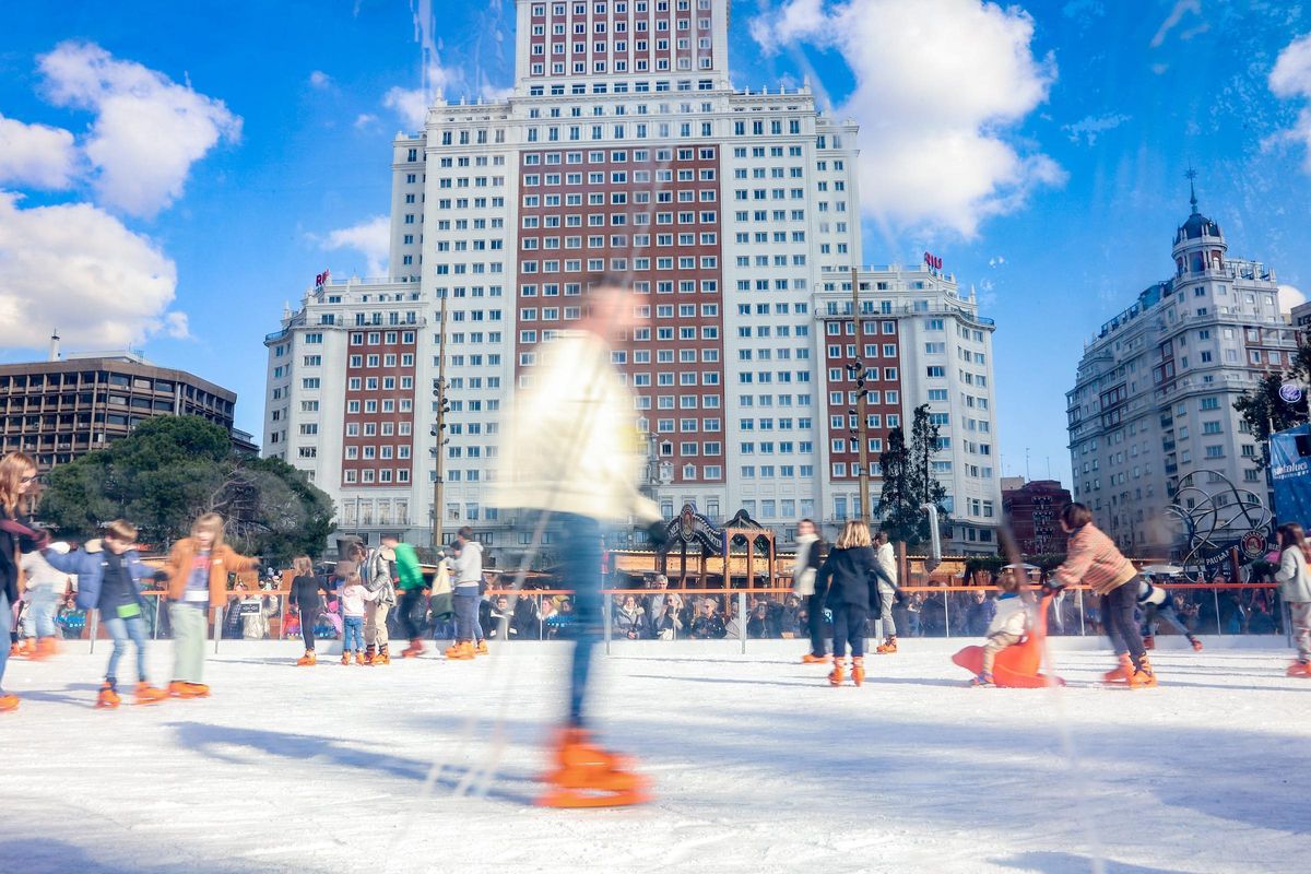 Varias personas patinan sobre hielo en la pista de Plaza de España, en Madrid.