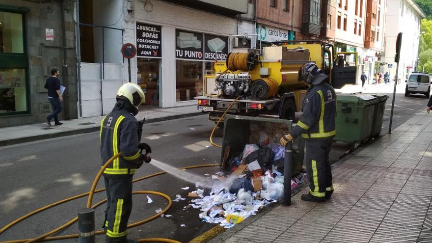 Dos bomberos sofocan el fuego, esta mañana, en Sama.