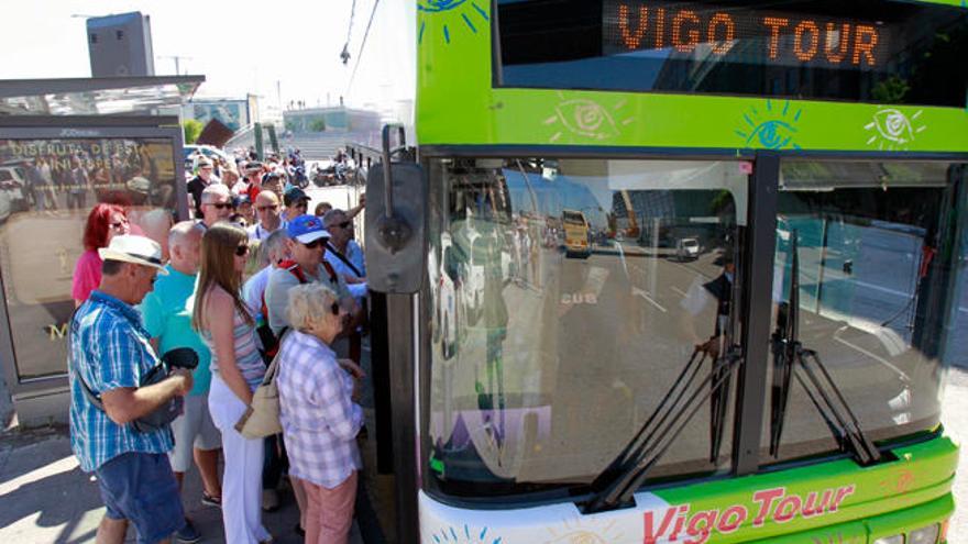 Un grupo de turistas se sube al bus turístico de Vigo // J. Lores