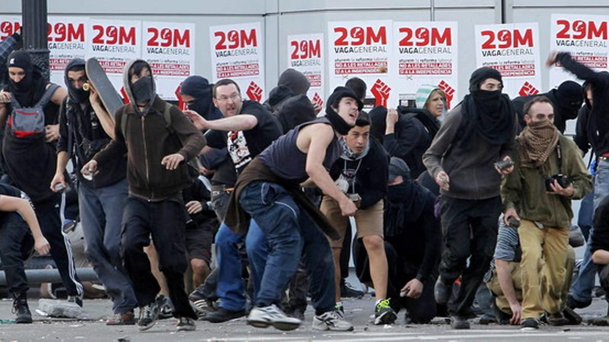 Manifestantes lanzan objetos a la policía durante los disturbios en la jornada de huelga.