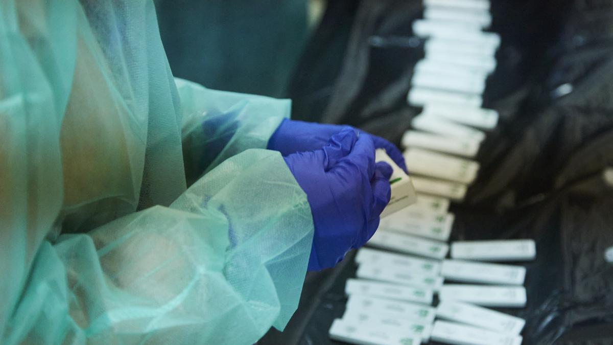 Una enfermera abre un test de antígeno para realizarle la prueba a un costalero durante el primer ensayo de costaleros de la Hermandad del Baratillo, con medidas covid-19, preparatorio a la Semana Santa de 2022, a 2 de febrero de 2022 en Sevilla.