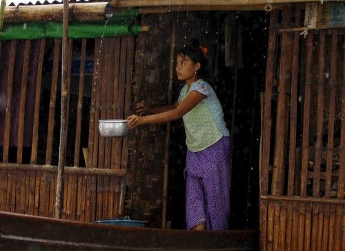 A woman collects rain water at her home in a flooded village outside Zalun Township, Irrawaddy Delta