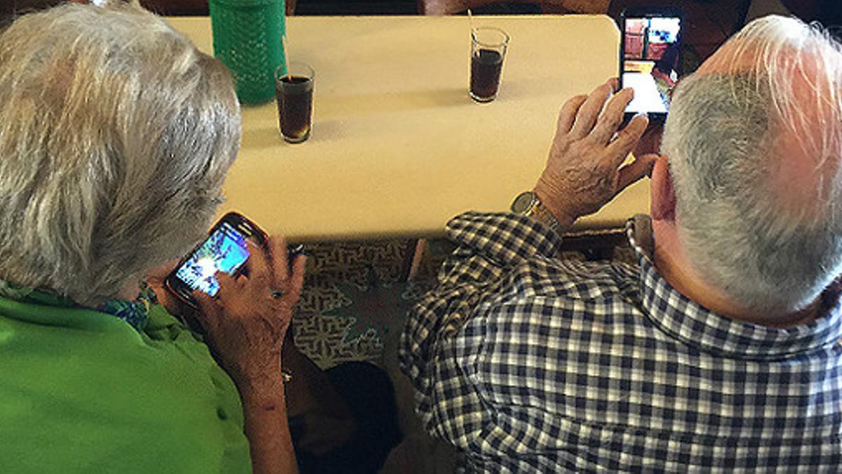 Dos jubilados toman un vermut mientras consultan internet en la bodega Quimet de gràcia.