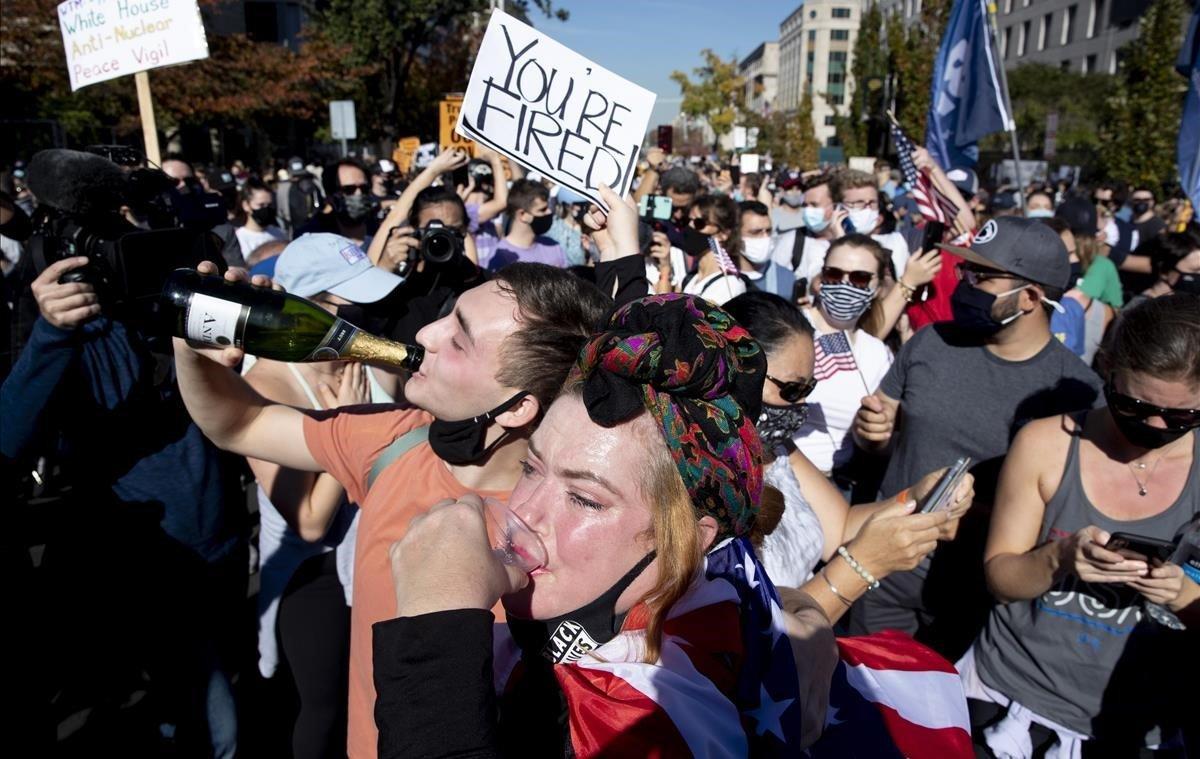 Jóvenes champán mientras la gente celebra la victoria de Joe Biden.