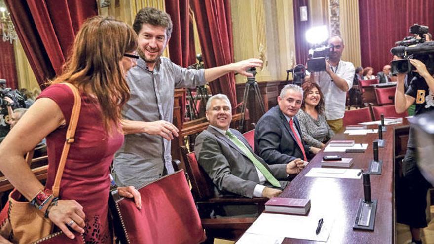 Laura Camargo y Alberto Jarabo, ambos de Podemos, bromean en sus escaños con Josep Melià y Jaume Font, de El Pi.