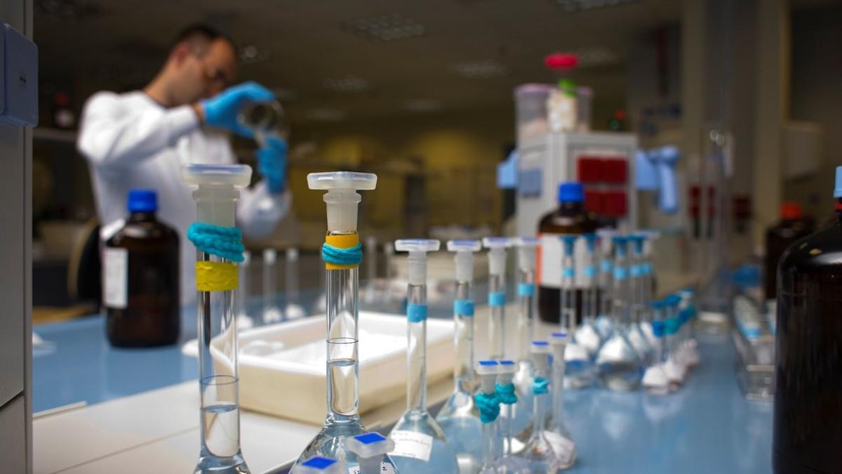 Un investigador vertiendo líquido de un vaso a una probeta en un laboratorio en Barcelona