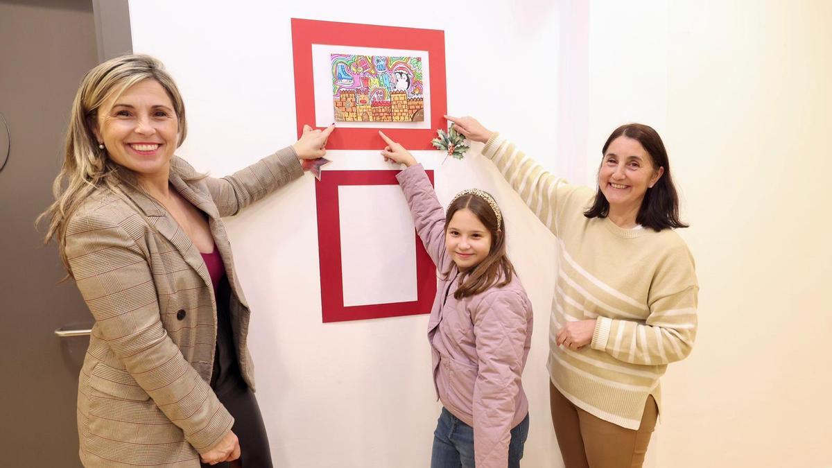 Noa Soto, coa alcaldesa e a concelleira, amosando a postal gañadora.