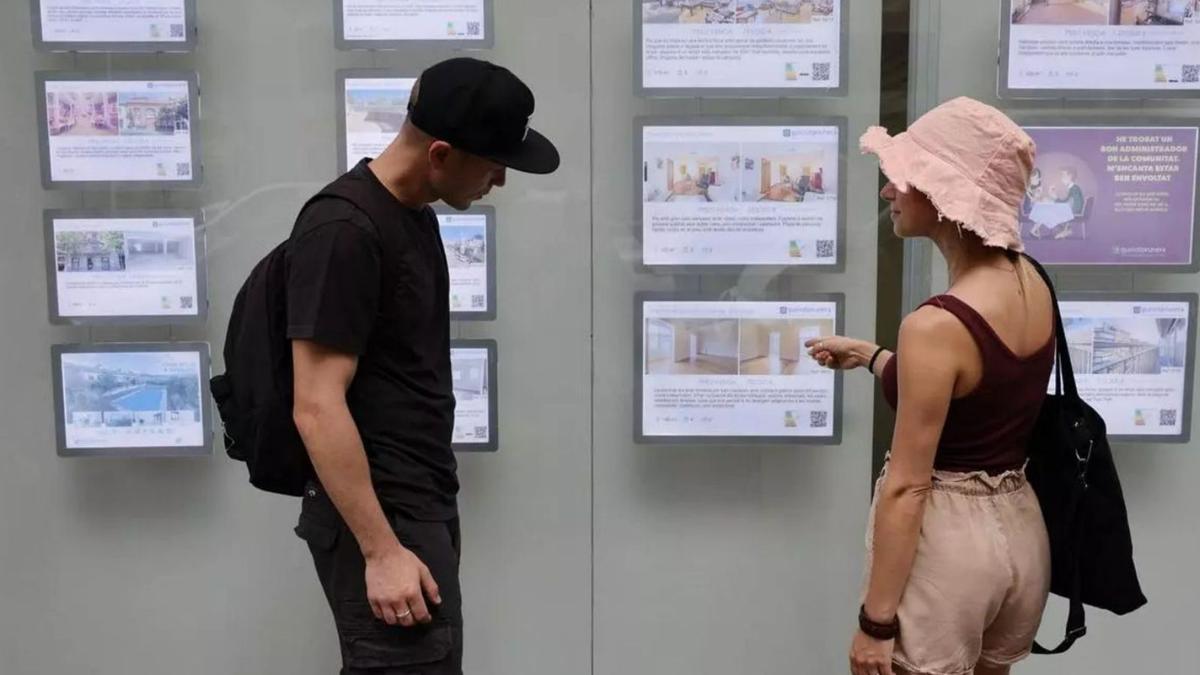 Dos joves observen els cartells d'una immobiliària. | ELISENDA PONS